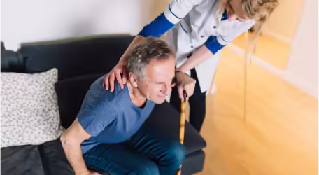 A man holding a stich standing up from the sofa