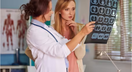 A doctor is showing a patient an MRI or X-ray.
